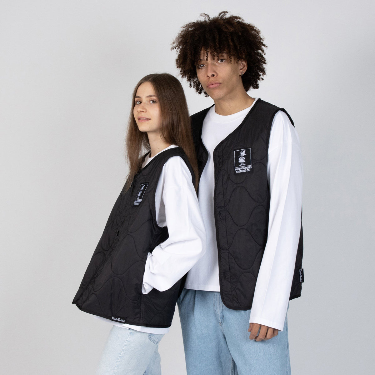 4. Male and female models wearing unisex black vests with NordicBuddies logo, standing back-to-back in studio