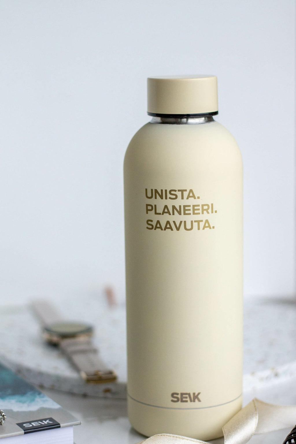 1. SEIK Unista water bottle in beige with motivational text, shown on a desk with accessories