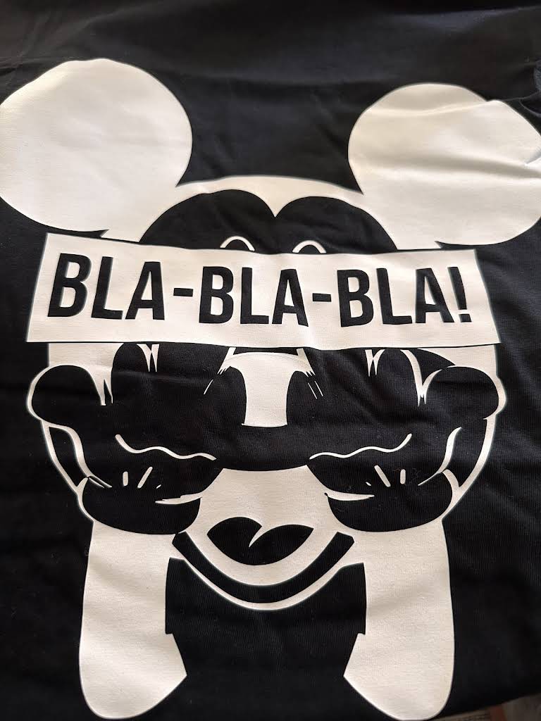 Black t-shirt with a white cartoon character holding a sign saying 'BLA- BLA- BLA!' on a black background.