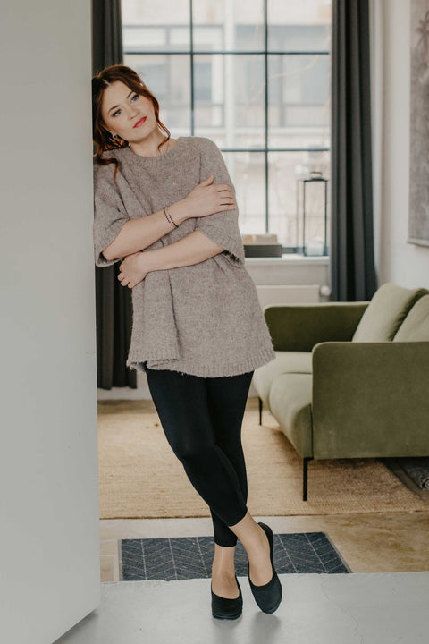 4. Woman wearing black upcycled ballerina shoes by Kira Sustainable, standing in a modern living room