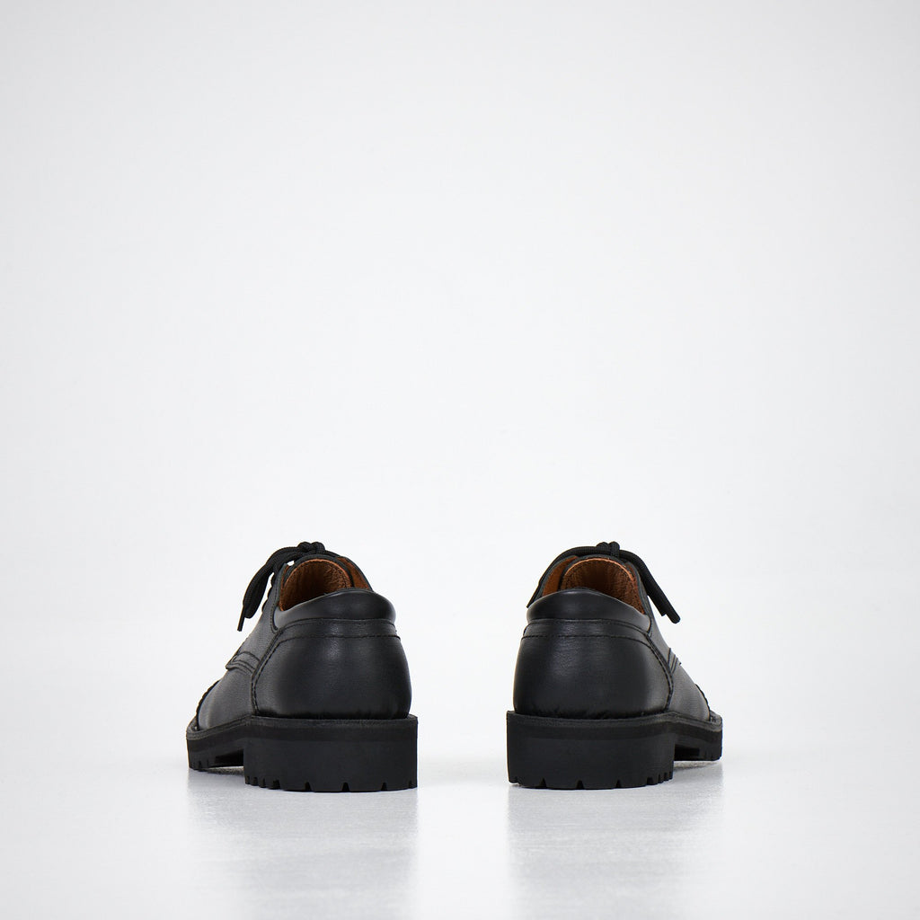 4. Unisex AIPI handmade leather shoes in black, rear view showing natural leather lining and sturdy construction, studio setting