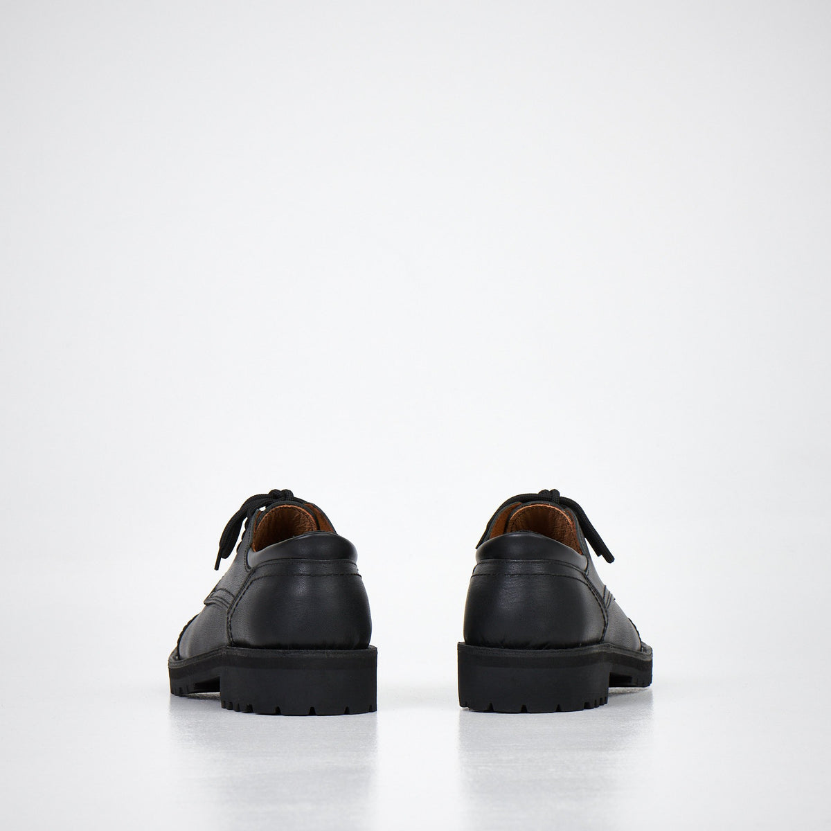 4. Unisex AIPI handmade leather shoes in black, rear view showing natural leather lining and sturdy construction, studio setting