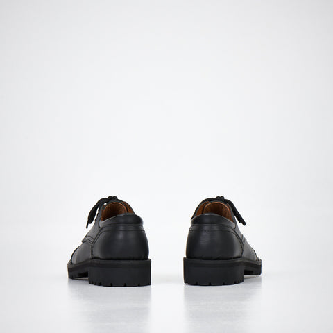 4. Unisex AIPI handmade leather shoes in black, rear view showing natural leather lining and sturdy construction, studio setting