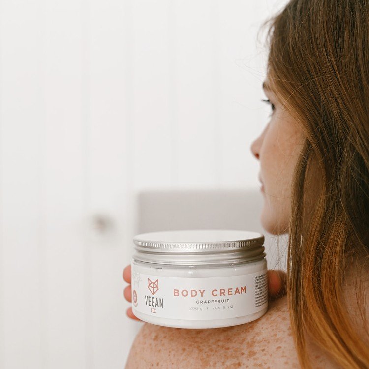 5. Woman holding Vegan Fox Grapefruit Body Cream jar against her shoulder in a lifestyle setting