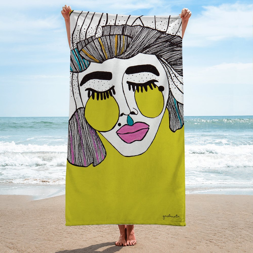 2. Garbanota Towel Veronika in yellow held by person on beach, featuring artistic face design