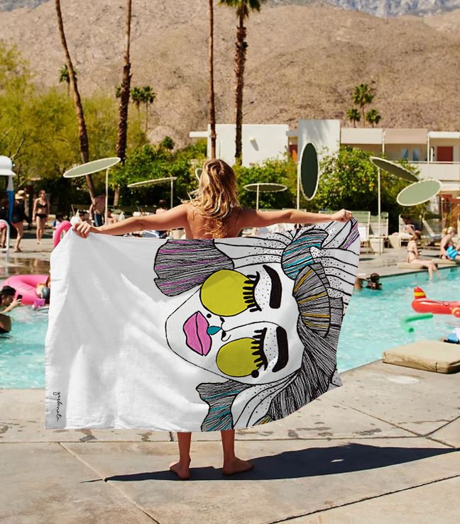 2. Woman holding Garbanota Towel Veronika with artistic face design by a poolside