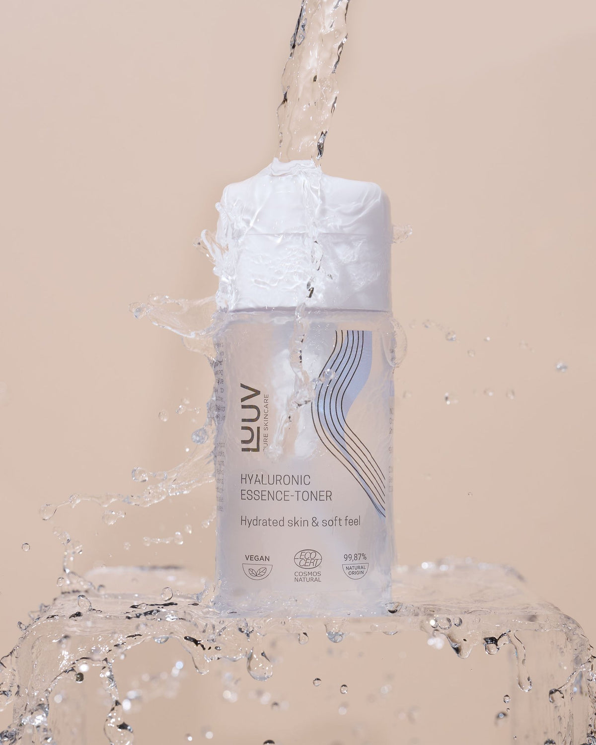 1. LUUV Hyaluronic Essence-Toner bottle with water splash on beige background, highlighting hydration and soft feel