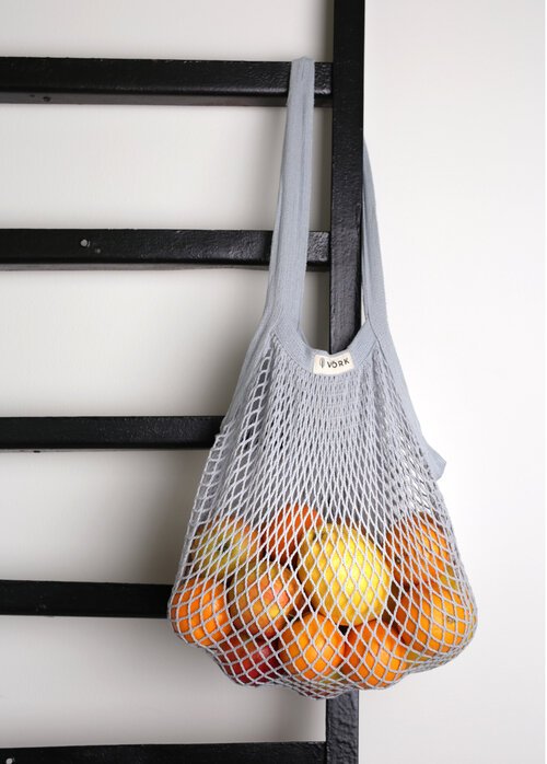 2. Grey VÕRK organic cotton string bag by Sidrunid filled with oranges, hanging on a black ladder