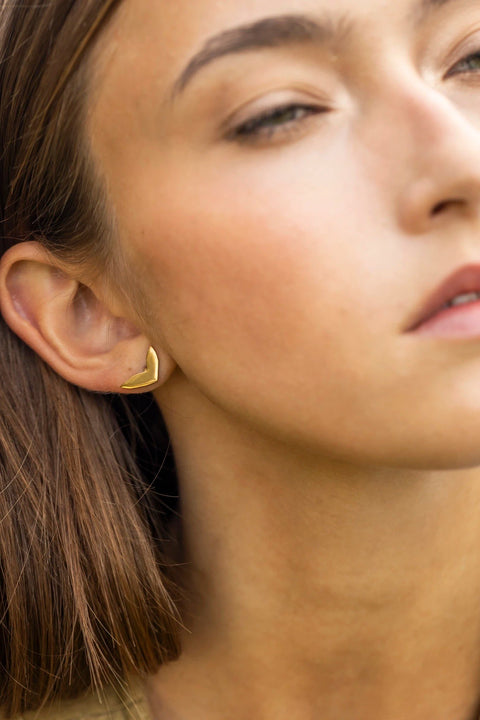 1. Woman wearing rose gold earring with polished finish, close-up on ear, outdoors