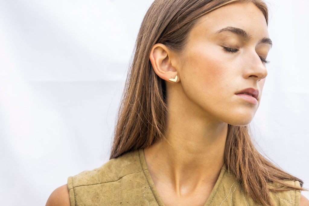 1. Woman wearing rose gold earrings with polished finish, side profile, outdoors