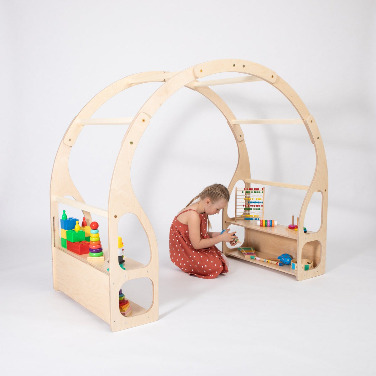 1. Child playing with toys on Montessori play stand made of birch plywood in a white studio setting