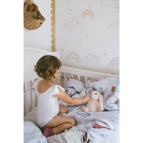 4. Child playing with a stuffed bunny in a crib with golden circle wall stickers