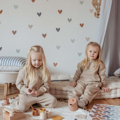 2. Two children in beige outfits sitting in room with Dekornik heart wall stickers in cappuccino and blue