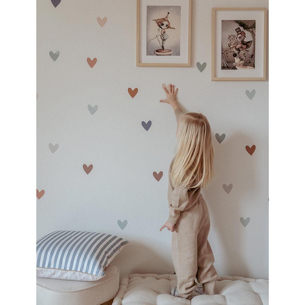 3. Child reaching for Dekornik heart wall stickers in cappuccino and blue on wall with framed art