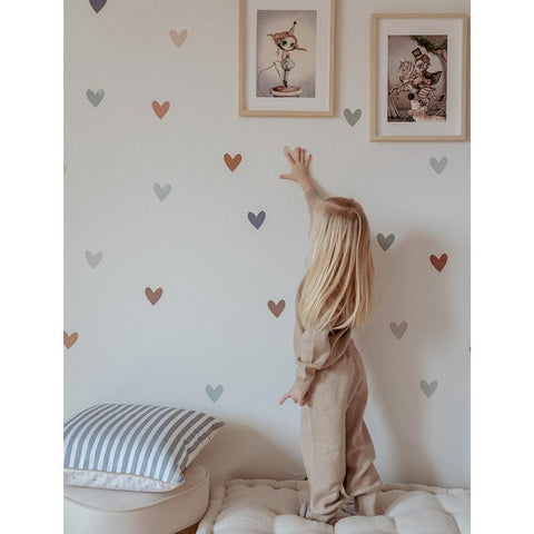 3. Child reaching for Dekornik heart wall stickers in cappuccino and blue on wall with framed art