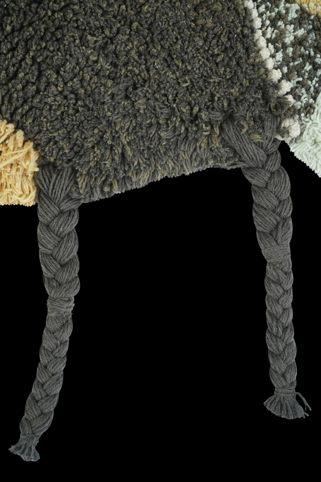 3. Close-up of braided dark gray legs on bee rug with fluffy texture