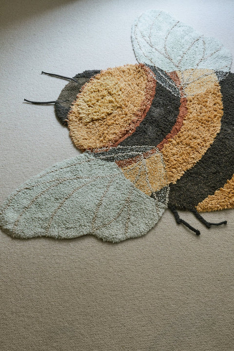 2. Bee rug with honey and dark gray stripes and light blue wings on a light carpet