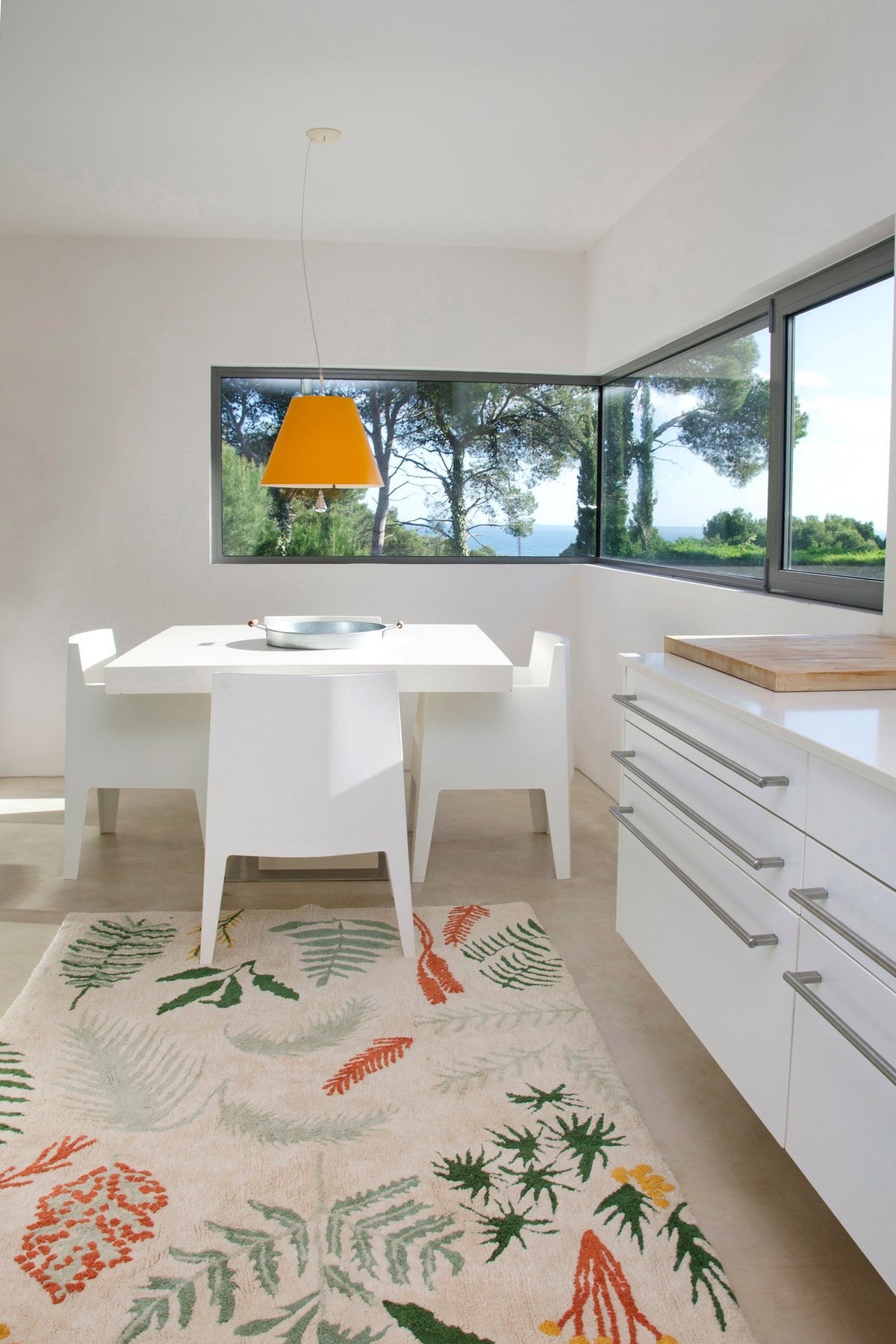 6. Botanical rug in a bright dining area with white furniture and large windows