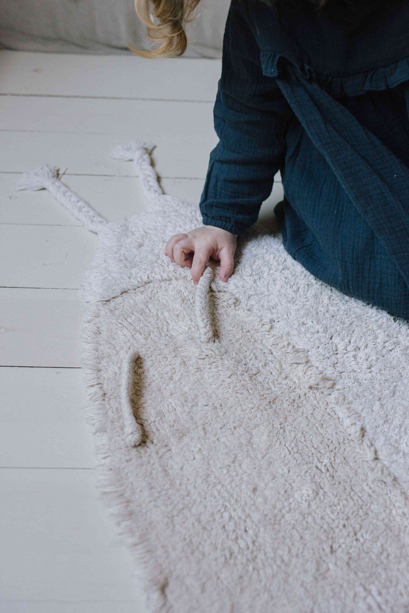 3. Close-up of child touching the natural-colored body of the snail-shaped rug