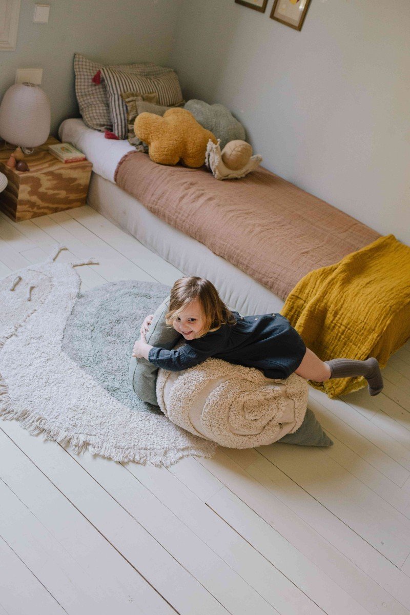 1. Child playing on snail-shaped rug in a cozy bedroom setting