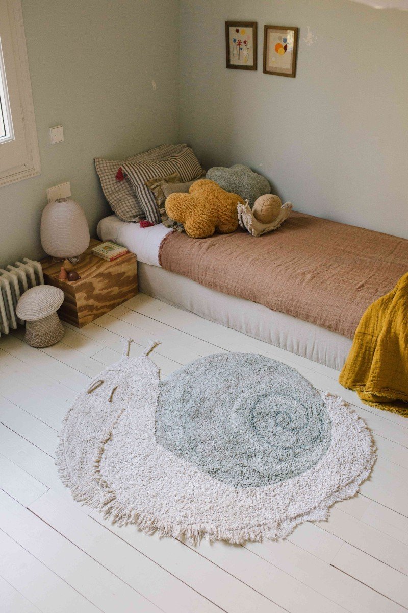 1. Snail-shaped rug in sage blue and natural colors placed in a cozy children's bedroom with a bed and toys