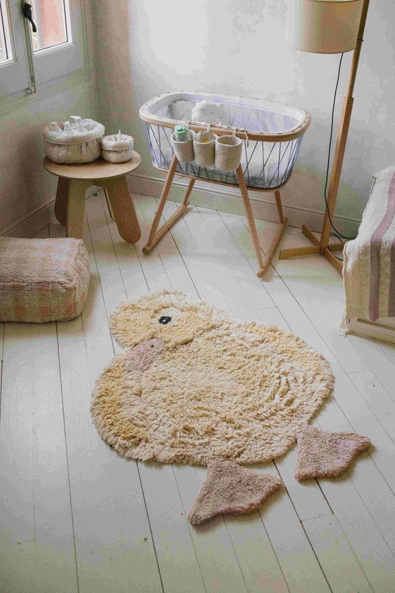 3. Light yellow duck-shaped rug with pink beak and feet in a nursery room with wooden furniture