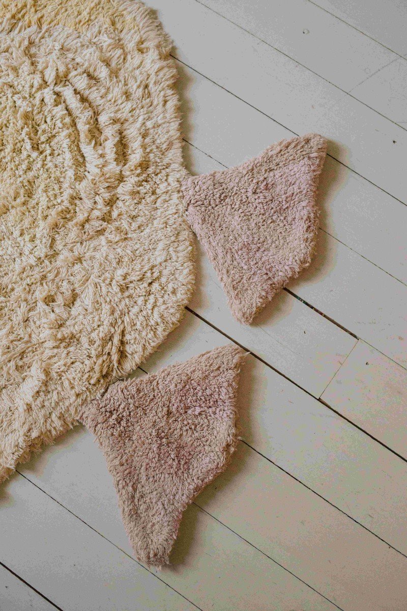 4. Close-up of pink textured feet of light yellow duck-shaped rug on wooden floor