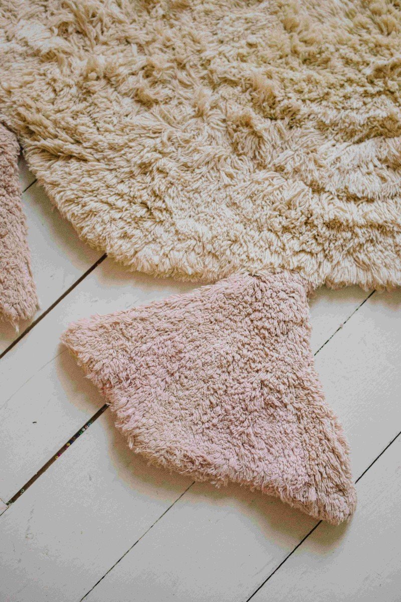 5. Detail of pink textured foot of light yellow duck-shaped rug on wooden floor