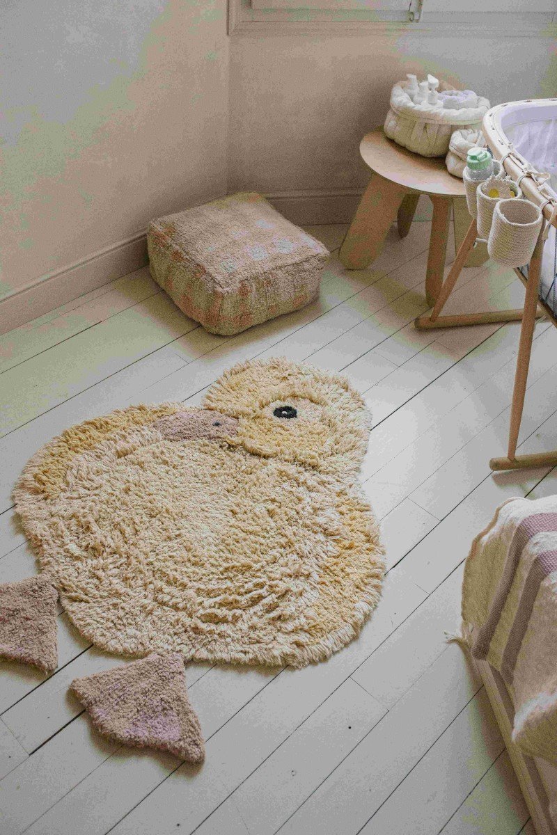 9. Light yellow duck-shaped rug with pink beak and feet in a nursery room with natural light
