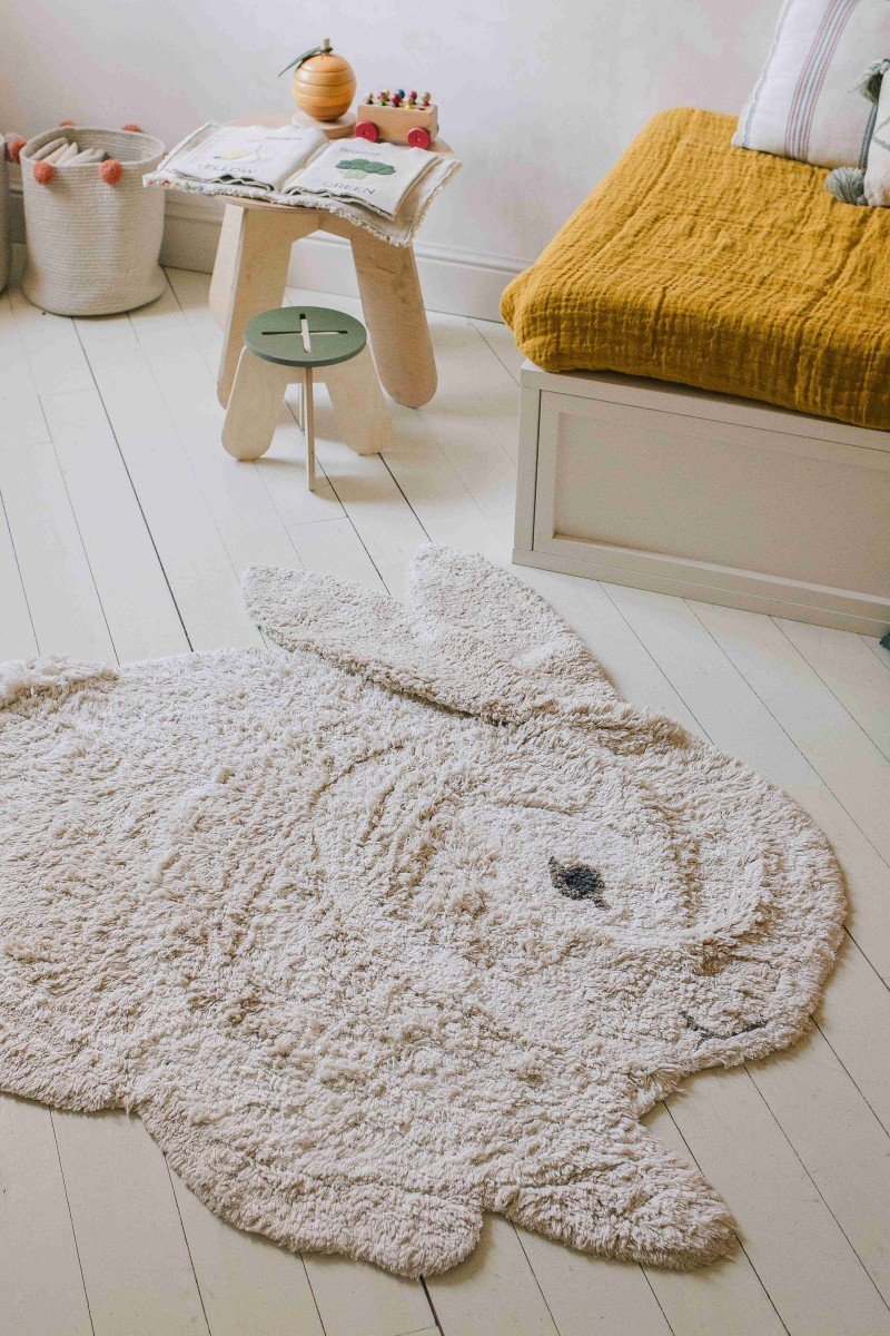 7. Bunny-shaped rug in natural and ivory on a wooden floor next to a cozy seating area