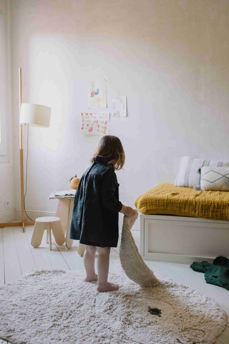 6. Child interacting with natural and ivory bunny rug in a warmly decorated room