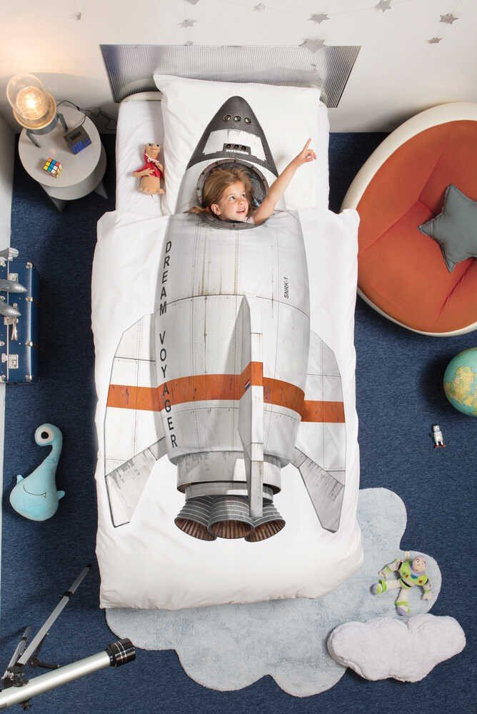 1. Child lying on a bed with a space-themed duvet, next to a blue cloud-shaped rug in a playful bedroom setting