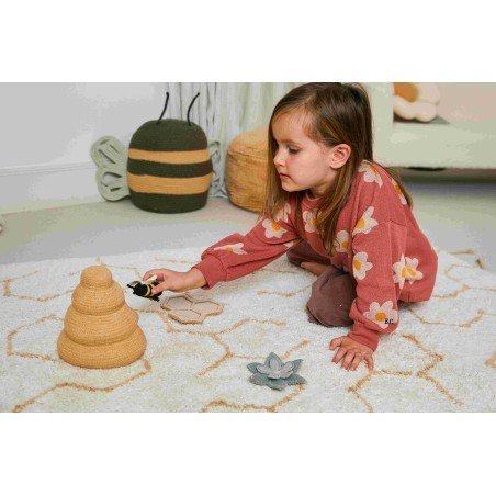 4. Child playing with bee and beehive accessories on ivory play rug with honeycomb pattern in a cozy room