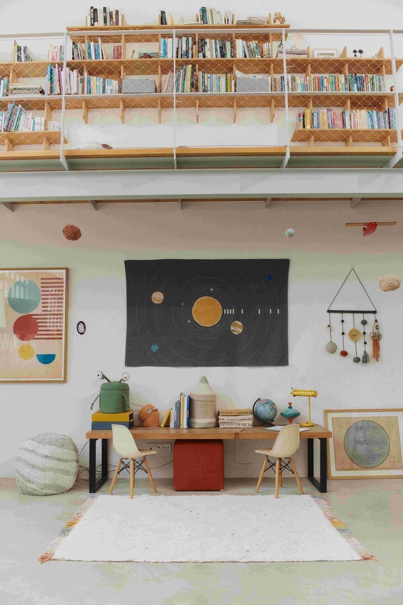 1. Lorena Canals Stardust rug in a study room with bookshelves and planetary decor, highlighting natural color and multicolored fringes