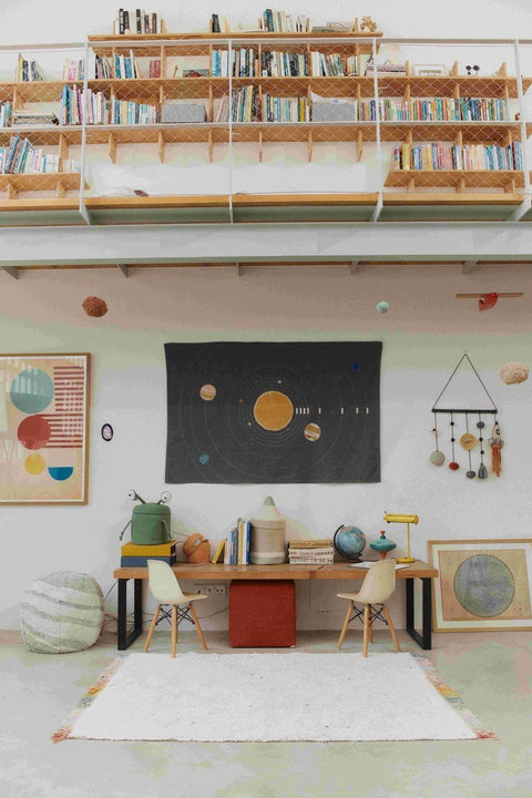 1. Lorena Canals Stardust rug in a study room with bookshelves and planetary decor, highlighting natural color and multicolored fringes