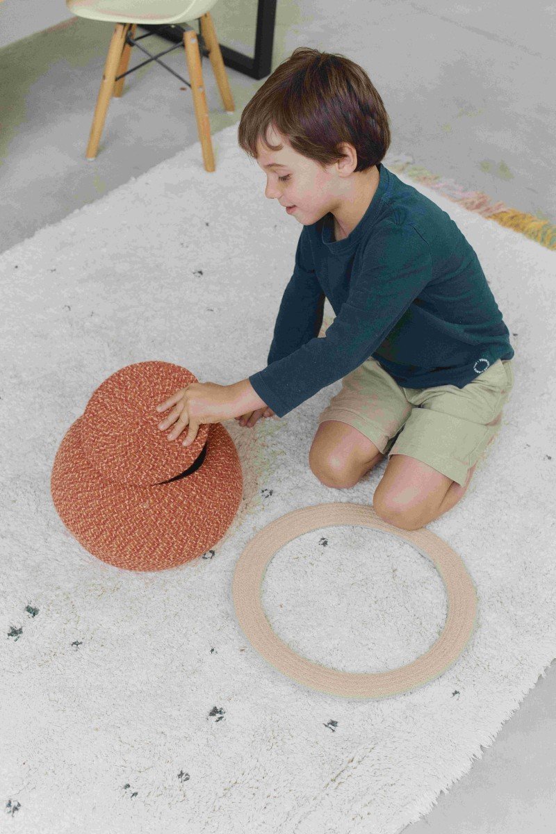 1. Child playing on Lorena Canals Stardust rug, showing natural color with dark dots and multicolored fringes