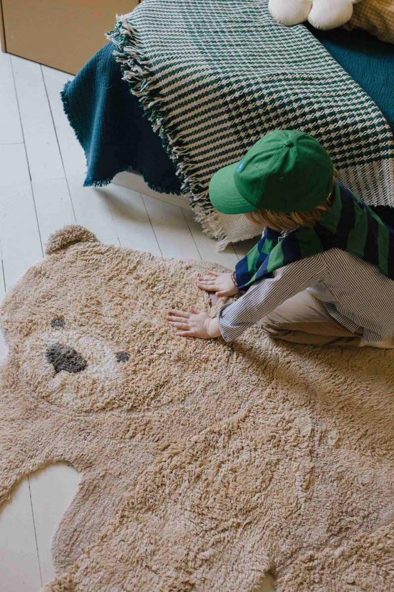 11. Child touching teddy bear rug's face in cozy room setting