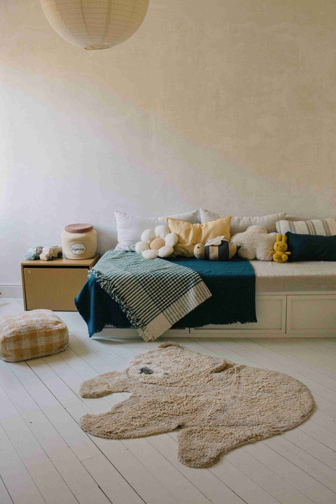5. Teddy bear rug in stylish room with bed, cushions, and pouf on white floor