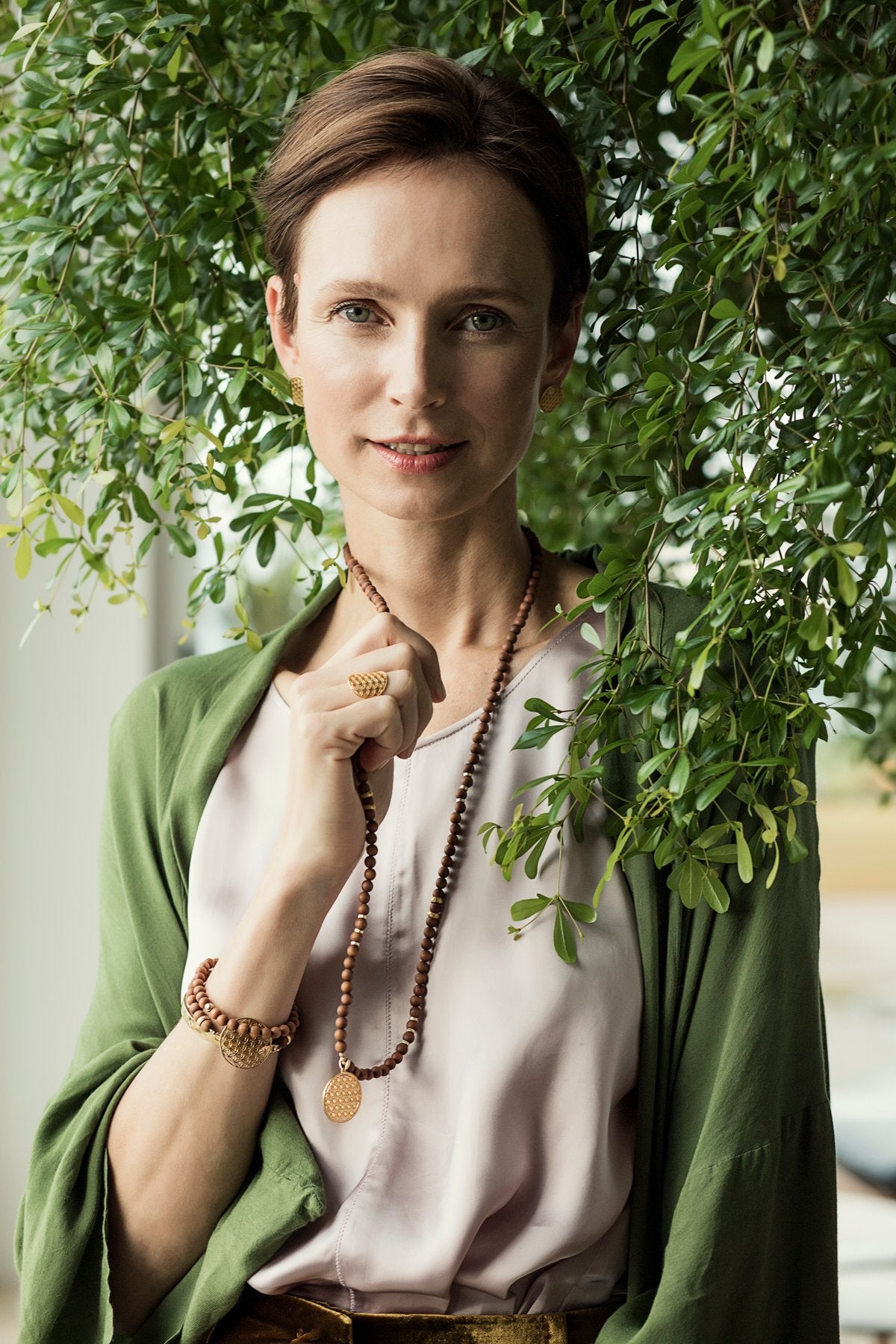 2. Woman wearing Flower Of Life Ring in a natural setting, styled with a green shawl and wooden necklace