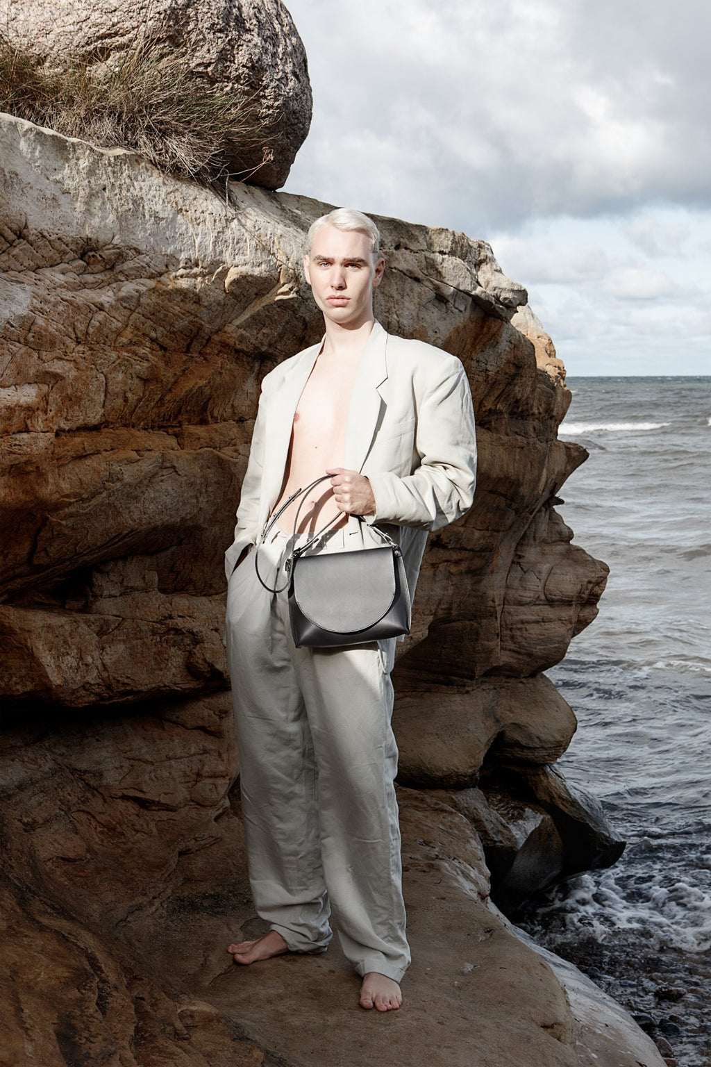 1. Person holding Stella Soomlais Undercover Lover handbag in natural rocky coastal setting