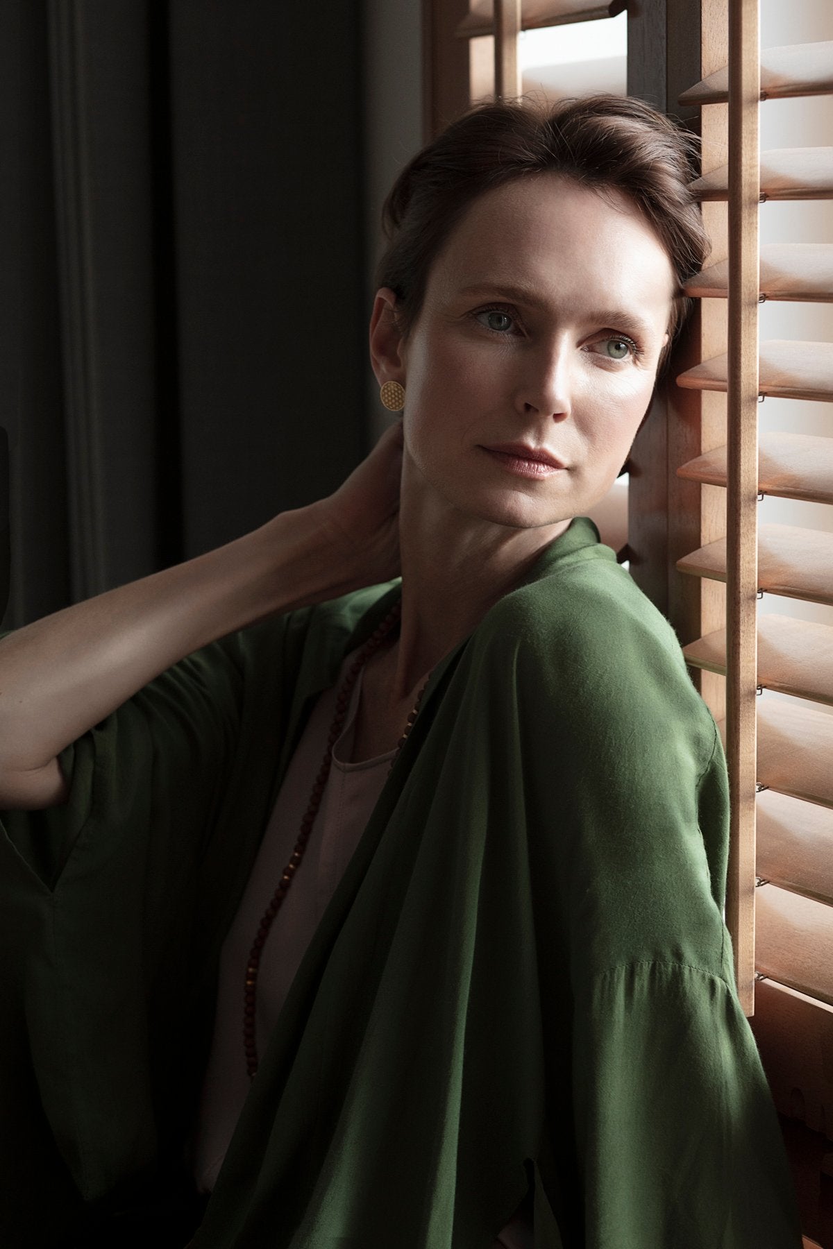 1. Woman wearing New Vintage by Kriss Flower Of Life gold stud earrings, shown in a lifestyle setting