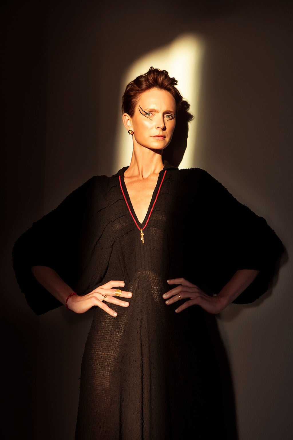 2. Woman showcasing Sekhmet Fire Necklace Ring in gold by New Vintage by Kriss, standing confidently in shadowed lighting