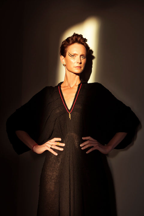 2. Woman showcasing Sekhmet Fire Necklace Ring in gold by New Vintage by Kriss, standing confidently in shadowed lighting