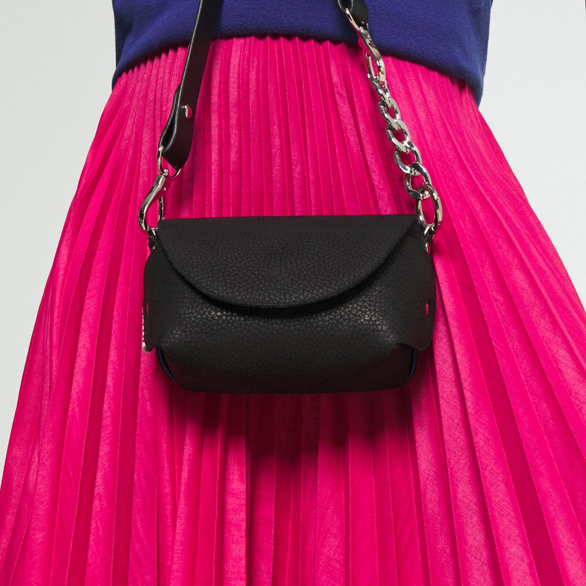 2. Black leather shoulder bag by Daz Studio with silver chain strap, styled with a pink pleated skirt