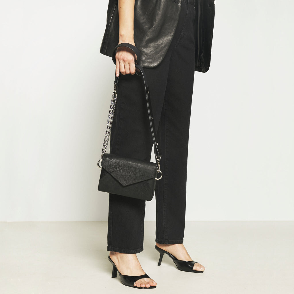 2. Women's handmade black leather envelope bag by Daz Studio styled as a handbag with chain detail, shown in lifestyle setting