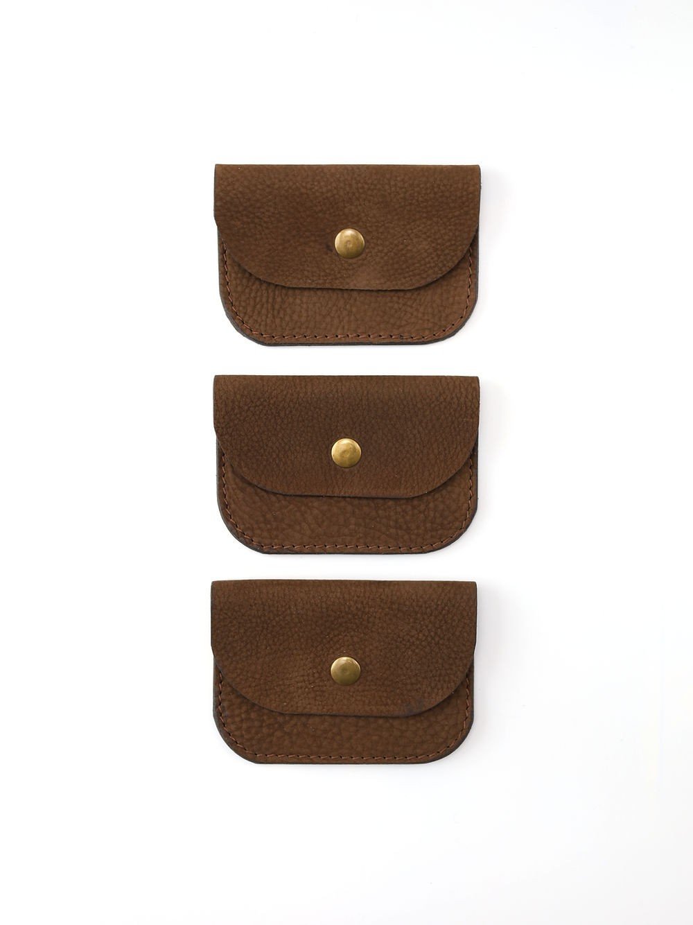 3. Trio of brown nubuck leather wallets with brass buttons displayed vertically on white background