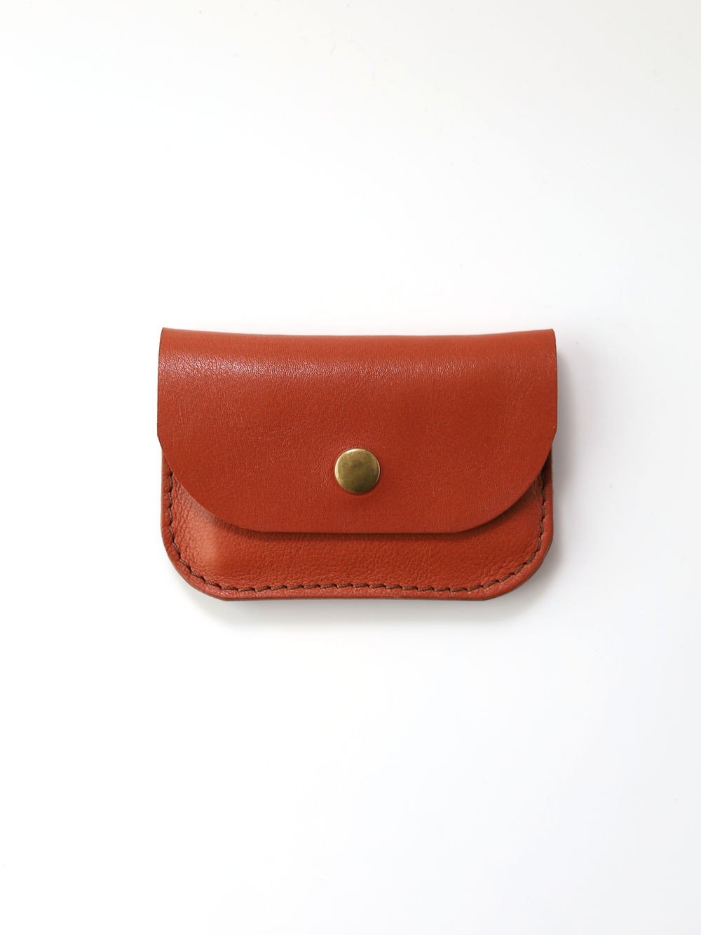 2. Studio shot of red clay leather wallet by Toks Visoks with brass button on white background