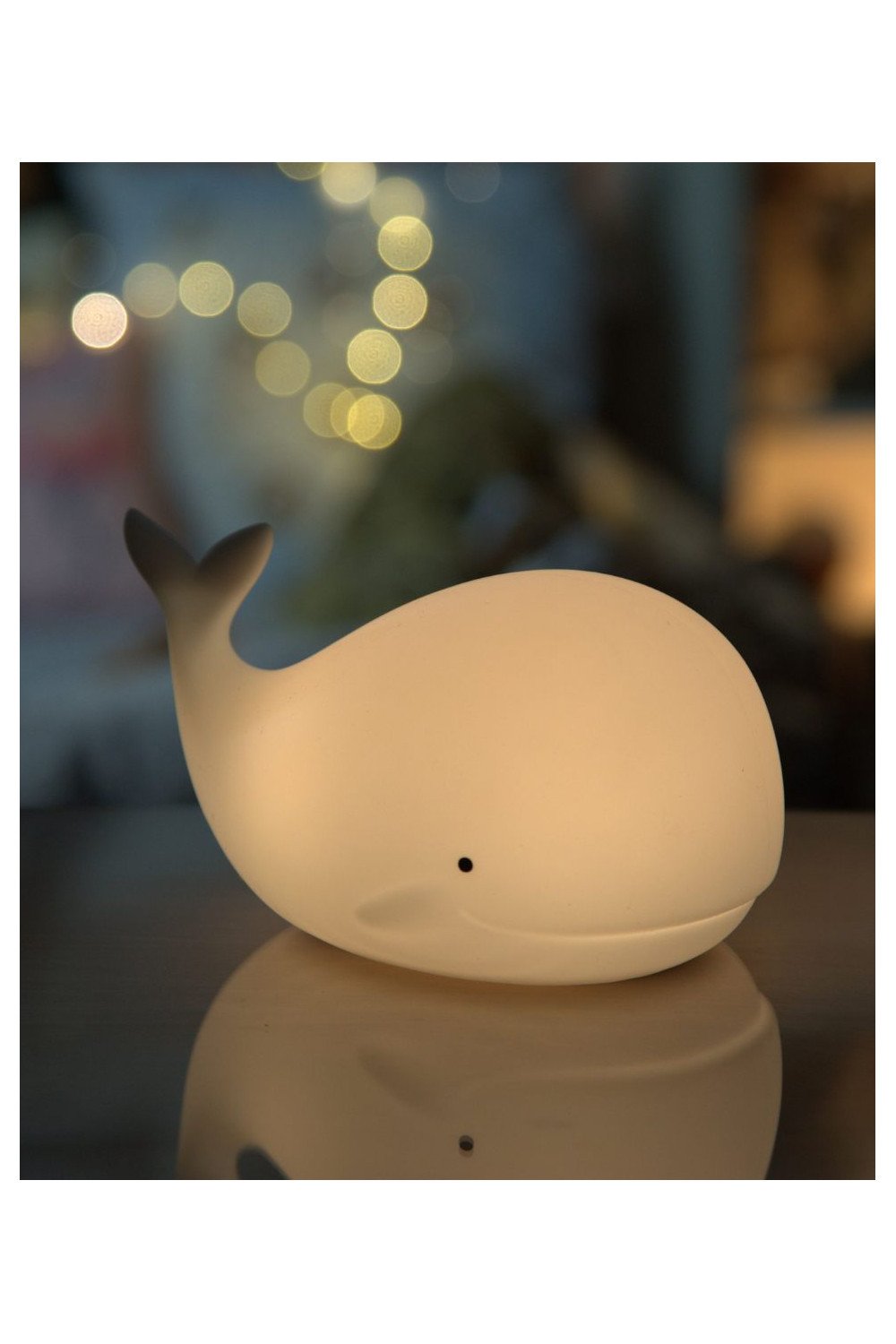6. Warm glowing whale silicone lamp by Rabbit & Friends with blurred lights in background