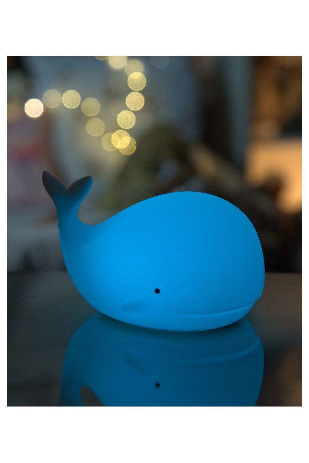 5. Blue glowing whale silicone lamp by Rabbit & Friends with blurred lights in background