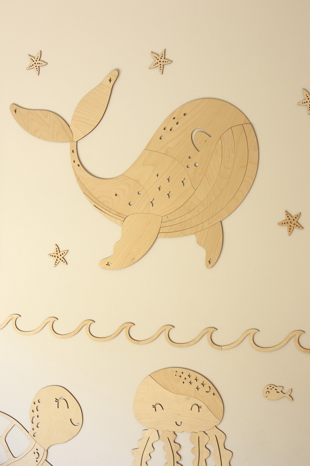 4. Wooden whale wall decoration with starfish and sea creatures like jellyfish and turtle on a beige wall